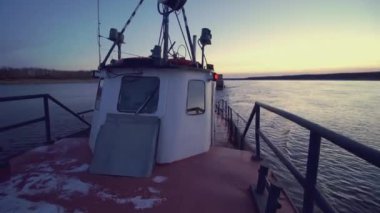 Mavna kargoyu çerçeveye çeker. Şarjör. Kargo mavnası ve karavanı suda yüzüyor. Bir kargo gemisi nehir boyunca ilerliyor. Arka planda ağaçlar.