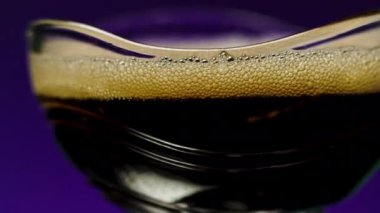 Baloncuklu koyu bir içecek. Borsa klipsi. İzole edilmiş arka planda koyu bar içkisi. Barda köpüklü alkol içeceği. 