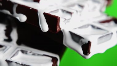 Koyu çikolataya zıt düşmeye ve beyaz çikolata jöleli şekere yakın durun. Borsa klipsi. Yeşil renkli anahtar arka planında lezzetli çikolata.