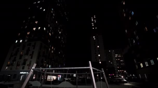 高層住宅ビルと子供の遊び場を持つ庭を持つ大きな都市の夜の背景 アクション 明るい窓のあるナイトシティ — ストック動画