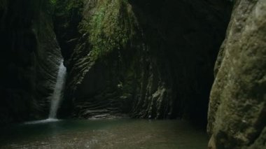 Orman geçidinde şelale. Yaratıcı. Ormandaki karanlık vadide güzel, gizemli bir şelale. Ormanda şelalesi ve göleti olan gizemli karanlık kayalar.. 