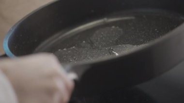 Yemek pişirme konsepti. Aksiyon. Üzerine yağın döküldüğü ve kızartma için sürüldüğü büyük siyah bir tava. Yüksek kalite 4k görüntü
