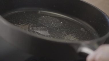 Kızartma ürünlerinin hazırlanması. Hareket. Önceden ısıtılmış bir tava yağ ile yağlanmış ve farklı yönlere çevrilmiş. Yüksek kalite 4k görüntü