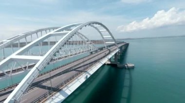 Denizdeki güzel asma köprü manzarası. Vuruldu. Güneşli bir günde turkuaz denizde beyaz bir köprü. Güzel, modern köprü. Arabalar deniz kenarında..