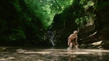 Ormandaki temiz nehir pınarındaki çocuk. Yaratıcı. Neşeli çocuk ormanda sıcak bir günde orman nehrinde serinliyor. Dağ ormanlarında dinlenin.. 