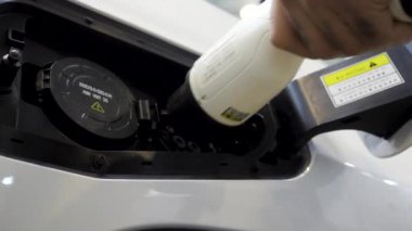 Açık hava elektrikli araç şarj tesisi. Medya. Ekoloji kavramı, erkek eli elektrik dolum istasyonu kullanıyor.