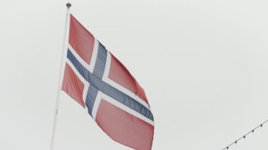 Norveç bayrağı. Aksiyon. Beyaz bir gökyüzünün üzerinde haçlı kırmızı bir tuval. Yüksek kalite 4k görüntü