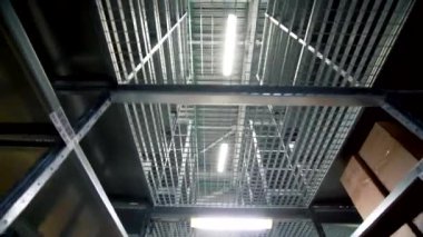 Geniş modern depodaki büyük boş metal rafların altında hareket. Yaratıcı. Parlak lambalar ve metal raflar