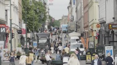 Norveç, Oslo - 27 Temmuz 2022: Birçok dükkan ve restoran ile kalabalık şehir caddesi. Başla. İnsanlar ve arabalarla dolu bir cadde.
