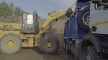 Taş ocağında farklı makineler çalışıyor. Sahne. Taşları ve kumu yükleyen traktör ve kamyonlarla endüstriyel arka plan 
