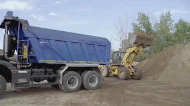 Taş ocağında farklı makineler çalışıyor. Sahne. Taşları ve kumu yükleyen traktör ve kamyonlarla endüstriyel arka plan 