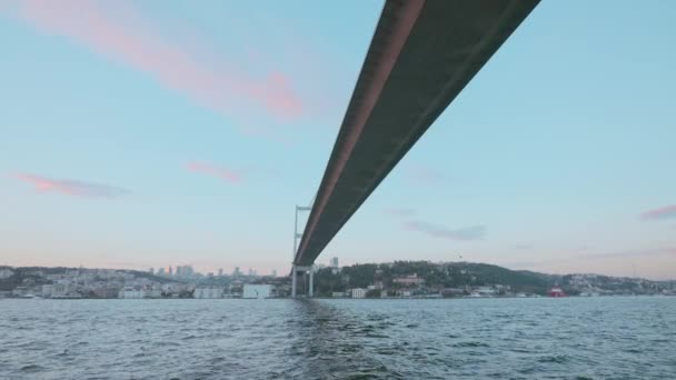 橋や川や海の下の景色を眺めることができます アクション 青い曇りの空の背景にある都市を横切る長い狭い橋 — ストック動画