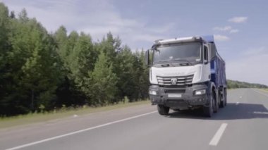 Sırbistan, Belgrad - 30 Temmuz 2021: Otoyolda giden çöp kamyonunun en üst görüntüsü. Sahne. İyi bir köy yolunda çocuklar için çöp kamyonu. Çöp kamyonu yeşil ormanın arka planında karayolu boyunca kargo taşır..