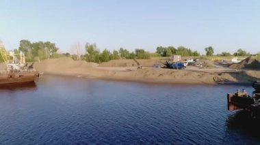 Kıyıda inşaat işi. Sahne. Nehir kıyısındaki inşaat işleri için ağır makineler ve mavnalar. İnşaat için kıyı bölgesinin boşaltılması. 