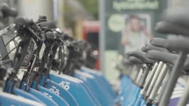 Kiralık bisiklet kuyrukları. Başla. Birbirinin aynısı bir sürü bisiklet sırada bekliyor. Modern şehirde kiralık sokak bisikletleri. Kiralık küçük toplu taşıma sistemi. 