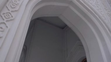 Beyaz bir ortodoks kilisesinin dışı. Sahne. Kilise binasının alt tarafında, duvarlarında oyma desenler var. 