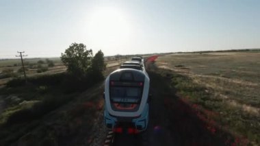 Hızlı trenle ülke seyahati. Vuruldu. Demiryolunda hızlı giden yolcu treninin hava görüntüsü ve yüksek hızlı kırsal kırsal araziyi geçmek