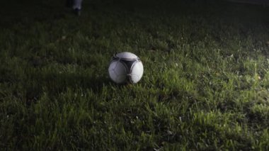 Futbol oyuncusunun çimlerin üzerinde topa vuruşunu yakından çek. Stok görüntüleri. Futbolcu geceleri stadyumda antrenman yapar. Futbolcu gece şampiyonada topa vuruyor.. 