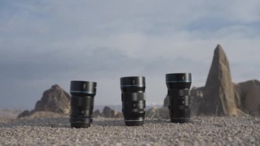 Üç profesyonel kamera lensi. Aksiyon. Kameradan büyük siyah lensler. Taşların üzerinde duruyorlar ve gri gökyüzünü görebiliyorsunuz. Yüksek kalite 4k görüntü