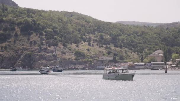 観光船は海辺の町の海岸から出航する アクション 小さな町との海岸の背景にある観光船 船舶と町との海岸の夏の風景 — ストック動画