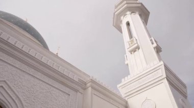 Müslüman beyaz tapınağının güzel minaresinin alt manzarası. Sahne. İslam dininin güzel beyaz tapınağı. Minareli beyaz tapınak, mavi kubbeler ve güneşli bir günde ay.. 