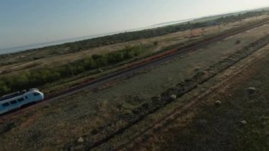 Drone trenin arkasına geçiyor. Vuruldu. Treni takip eden İHA 'nın üst görüntüsü. Hızlı trenin arkasındaki sinematik hareket tarlaların ve güneşin arka planında. 
