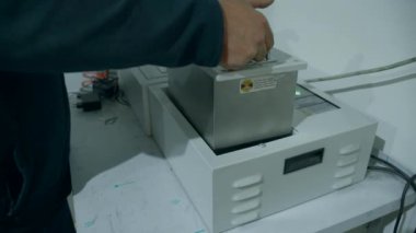 İtalya, Roma - 10 Ağustos 2022: Makineye pil yerleştiren işçilere yakın çekim. Yaratıcı. Sanayi fabrikasının bataryası. Depoda mekik rafları için pil kurulumu.