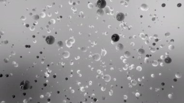 Gri bir zeminde tek renkli parçacıklar yavaşça uçuyor. Hareket. Soyut boşluktaki küçük küreler