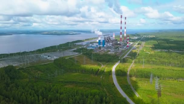 都市工業地帯と広い川の空中視野 クリップ 夏の森の上を飛行し 明るい空の背景にある発電所 — ストック動画