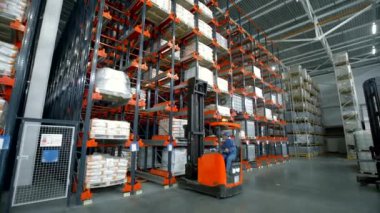Kaliforniya-ABD, 6-2022: Yaratıcı. Mavi üniformalı büyük bir depoda çalışan ve beyaz poşetlerde paketlenmiş çeşitli siparişler toplayan bir adam. Yüksek kalite 4k görüntü