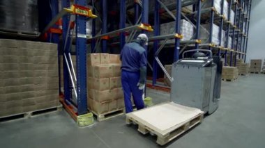 Kaliforniya-ABD, 6-2022: Yaratıcı. Mavi üniformalı büyük bir depoda çalışan ve beyaz poşetlerde paketlenmiş çeşitli siparişler toplayan bir adam. Yüksek kalite 4k görüntü