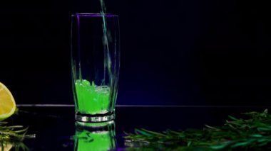 İçkili mavi arka plan. Borsa klipsi. Üzerine tarhun dökülen parlak bir zemin ve yanında köknar dalı olan bir limon. Yüksek kalite 4k görüntü