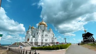 Yeşil bir tepede Ortodoks beyaz taş kilisesi. Klip. Yeşil ağaçlarla çevrili açık bir manzara ve turistlerin gittiği altın kubbeleri olan beyaz bir tapınak. Yüksek kalite 4k görüntü