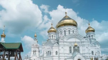 Altın kubbeli beyaz bir kilisenin havadan görünüşü. Şarjör. Bulutlu bir arka planda, büyük, güzel bir ortodoks kilisesi.