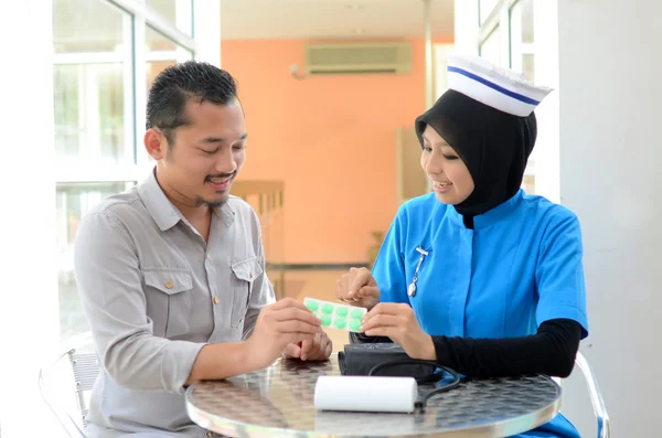 Paciente musulmán confiado revisando la presión arterial por enfermera —  Fotos de Stock