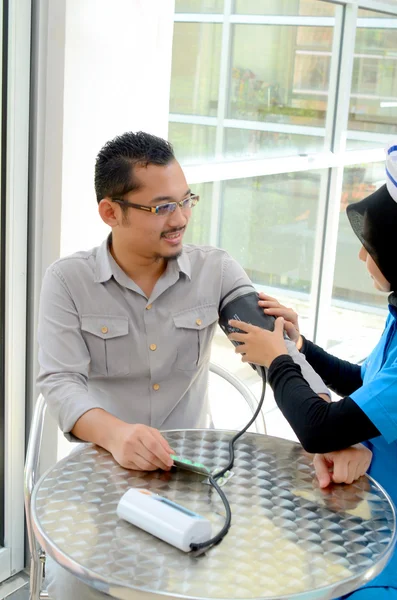 Paciente muçulmano confiante verificando a pressão arterial por enfermeira — Fotografia de Stock