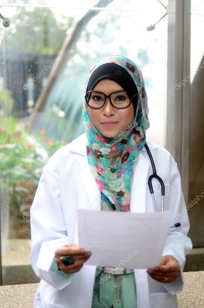 Young asian muslim woman doctor in head scarf smile while holding medical report
