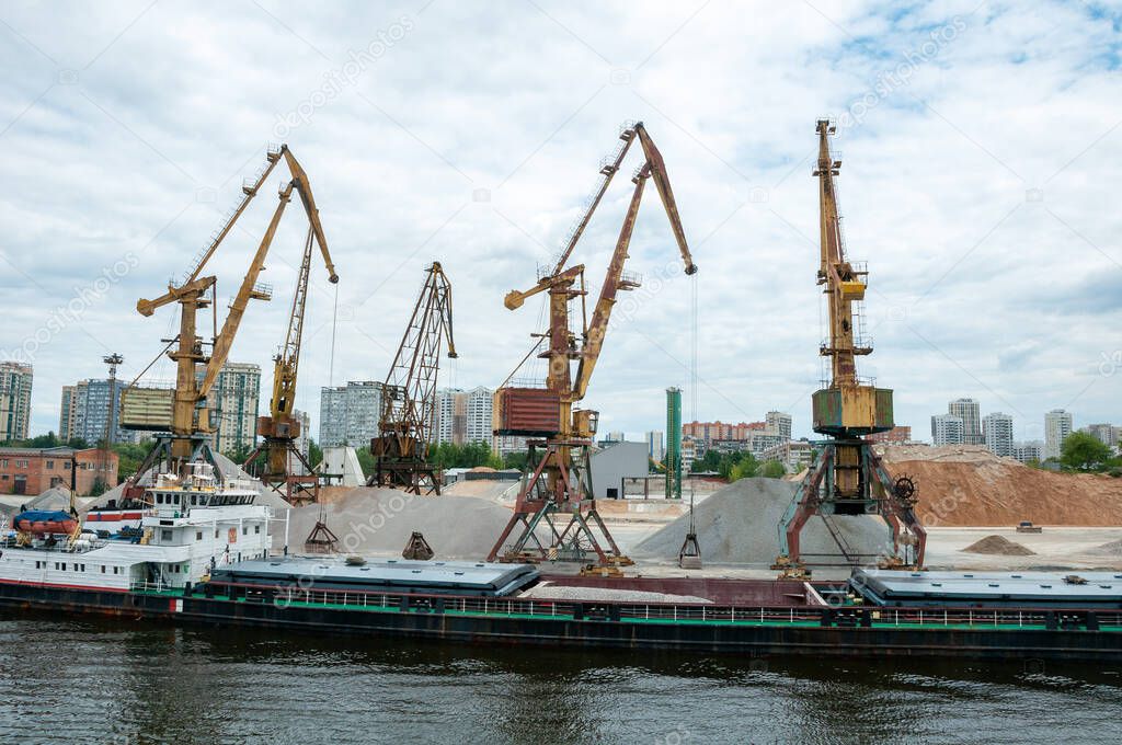 Port work loading and unloading the barge with sand and gravel