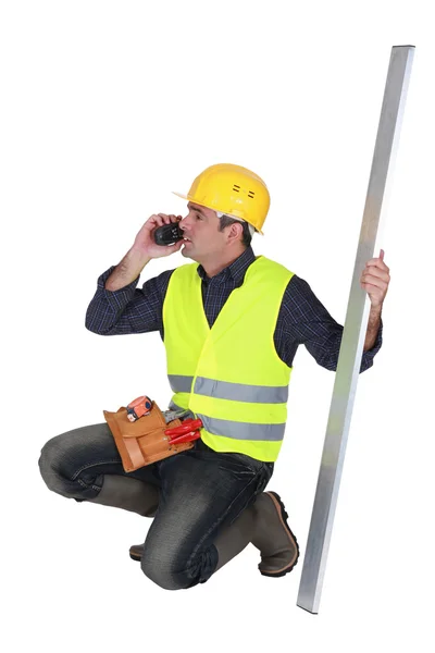 Builder holding a girder while talking on the phone — Stock Photo, Image