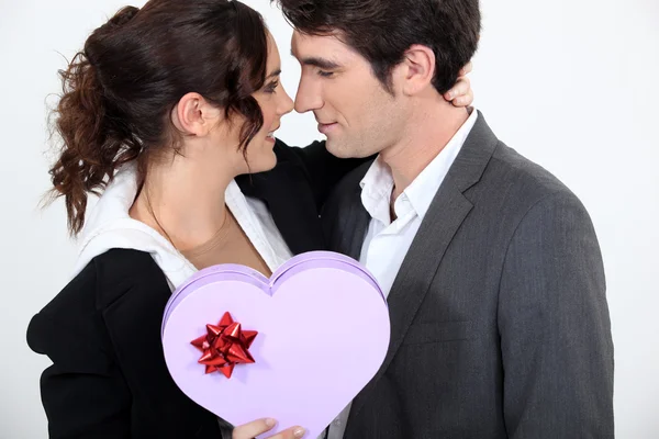 Casal segurando caixa em forma de coração de chocolates — Fotografia de Stock