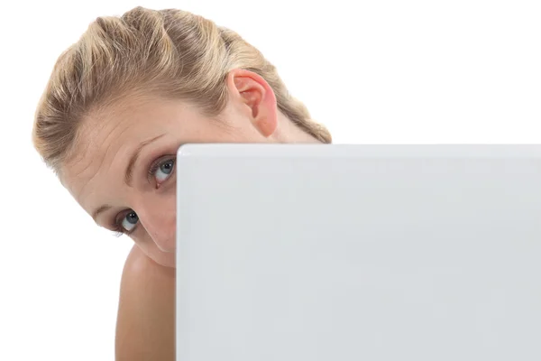 Vrouw gluren uit achter haar laptop — Stockfoto