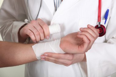 Doctor wrapping gauze around a patient clipart