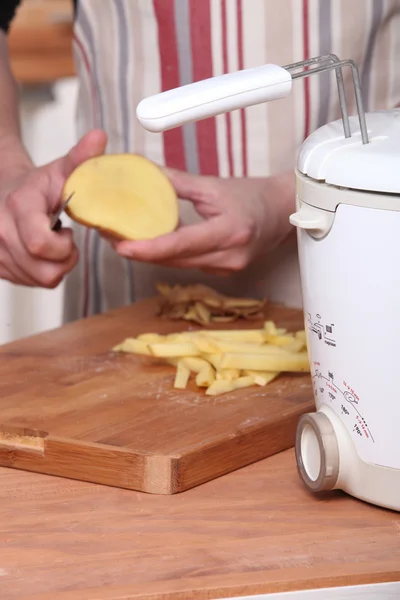 Een man schillen aardappelen en een friteuse — Stockfoto