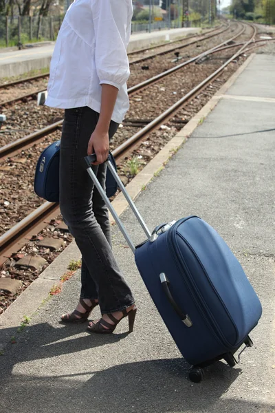 Mujer esperando en un andén de tren con una maleta —  Fotos de Stock