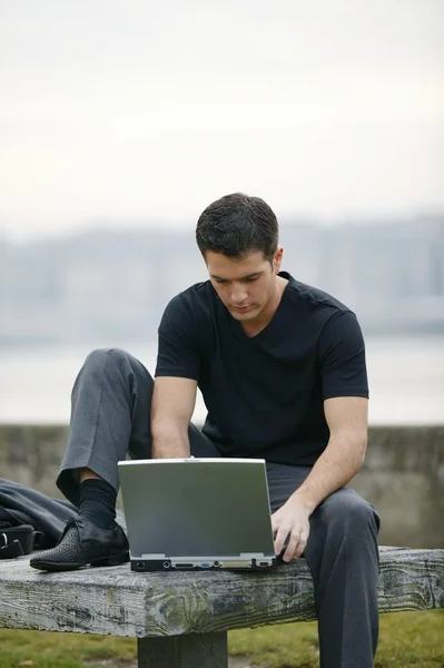 Muž používající svůj laptop venku — Stock fotografie