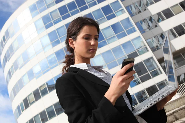 Morena mujer de negocios se paró al aire libre con portátil y móvil —  Fotos de Stock