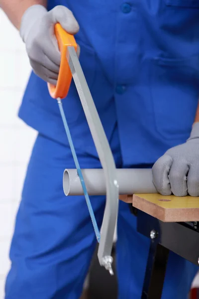 Hantverkare skära ett rör med en såg — Stockfoto