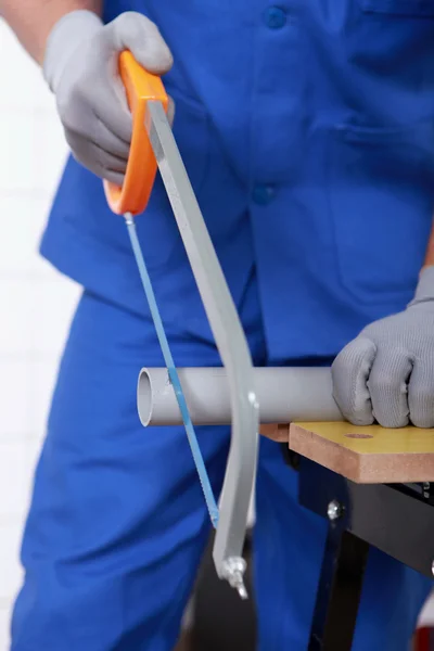 Craftsman cutting a pipe with a saw — Stock Photo, Image