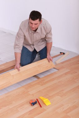 Labourer slotting together laminate flooring clipart