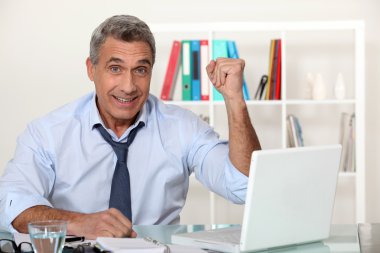 Excited businessman with a laptop clipart